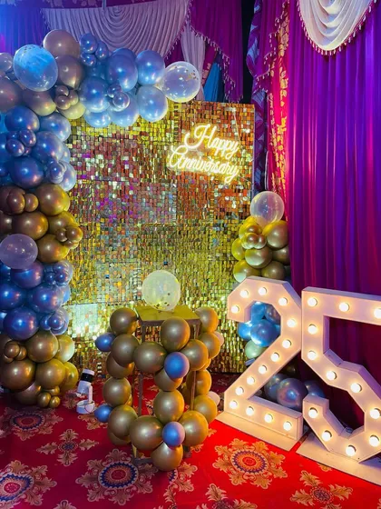 I love celebrating big milestones, like this 25th anniversary party. The setup features a glamorous gold sequin backdrop, a "Happy Anniversary" neon sign, and large, illuminated marquee numbers to make the occasion feel truly special.