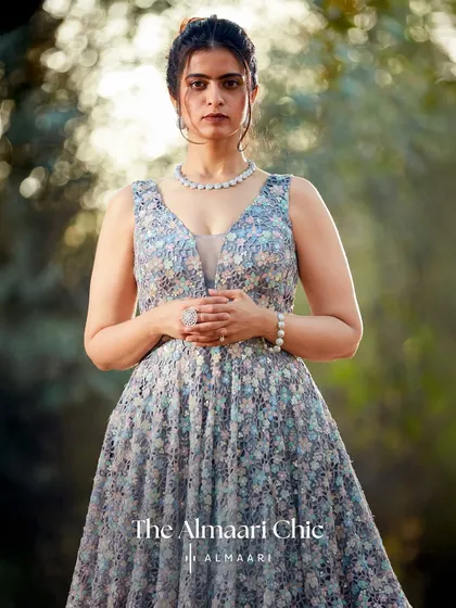 A closer view of the floral evening gown, showcasing the delicate texture of the fabric and the flattering V-neckline. The pearl jewellery adds a classic, sophisticated touch.