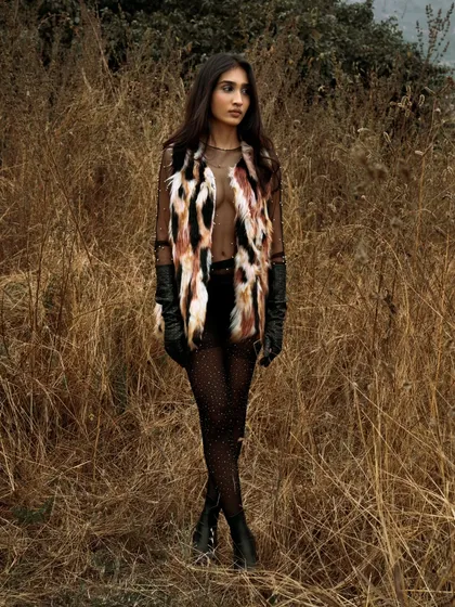 A full-length standing shot that showcases the fashion against the wild, untamed backdrop. The image has a free-spirited and adventurous feel.