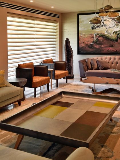 This living room is a composition of textures and forms. A large, tray-like coffee table with a geometric leather pattern sits before a tufted sofa, with a bold modern artwork adding a splash of energy.