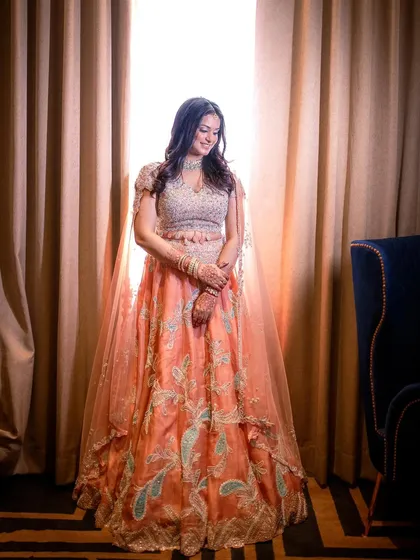 A full-length shot of the bride-to-be, showcasing her flowing peach and blue lehenga.