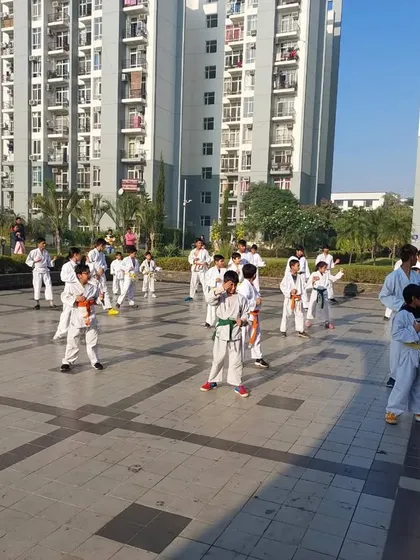 Students spread out and practicing their forms during an outdoor belt exam. Discipline is visible in their coordinated movements.