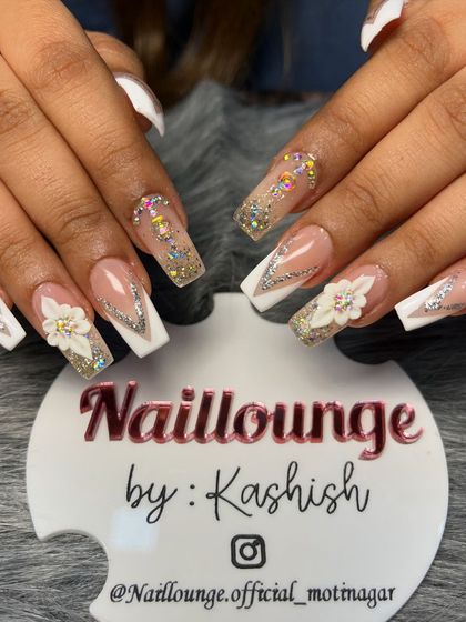 A stunning bridal set with white V-tips, iridescent stones, 3D flowers, and glitter accents on long square nails.