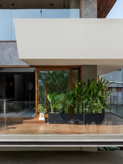 This view shows a cantilevered balcony with a solid white parapet, creating a private outdoor space. The design juxtaposes the solid mass with the transparency of the glass railing on the lower terrace.