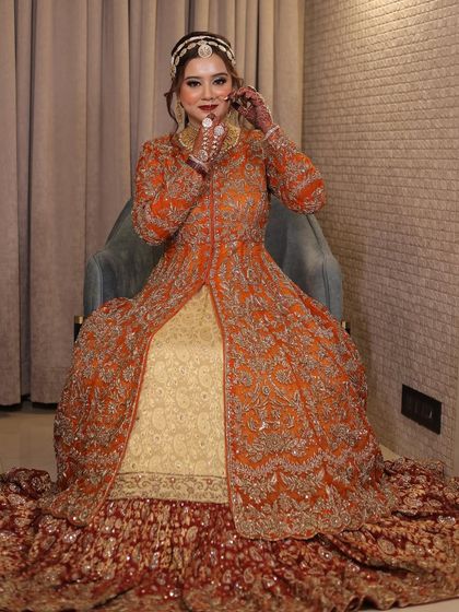 A full-length portrait of the bride in her magnificent orange and red bridal gown. The look is royal, unique, and absolutely stunning.