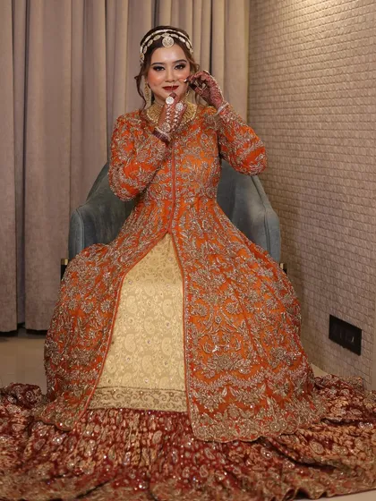 A full-length portrait of the bride in her magnificent orange and red bridal gown. The look is royal, unique, and absolutely stunning.