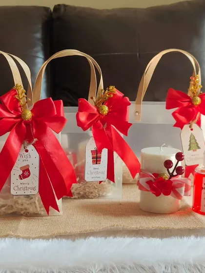 Preparing multiple Christmas gift bags for a client. Each one is finished with a big red bow and a "Merry Christmas" gift tag.