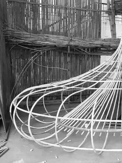 The bare metal skeleton of the oversized light fixture before the weaving process began. This image reveals the structural engineering required to support such a large, handcrafted installation within a commercial space.