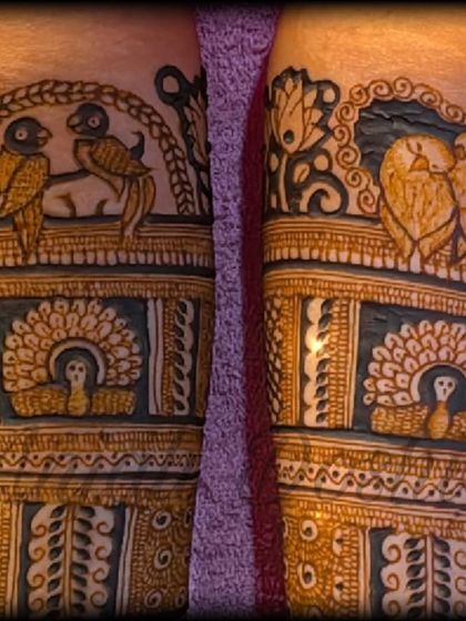 A close up of the fresh henna paste, showing the details of lovebirds and a bride figure before the design is complete.