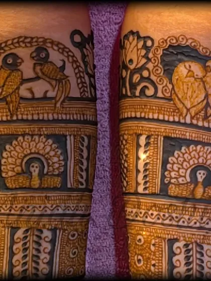 A close up of the fresh henna paste, showing the details of lovebirds and a bride figure before the design is complete.