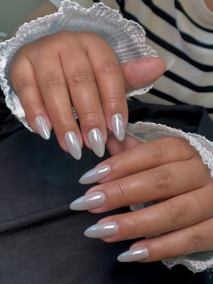 This view, with the delicate lace cuffs, highlights the simple elegance of a solid pearl chrome manicure.