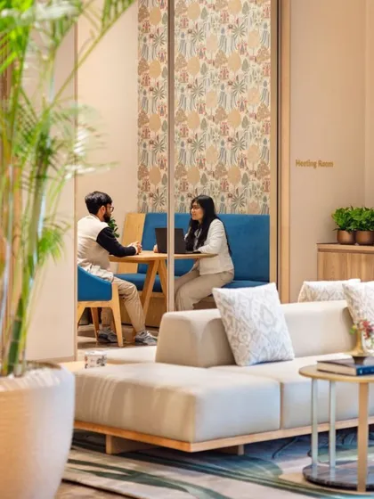 In our clubhouse designs, we create pockets for quiet connection. This nook in the Godrej Woods Clubhouse offers a comfortable space for informal meetings or personal work, framed by lush greenery and accented with patterned wallpaper to add a touch of character.