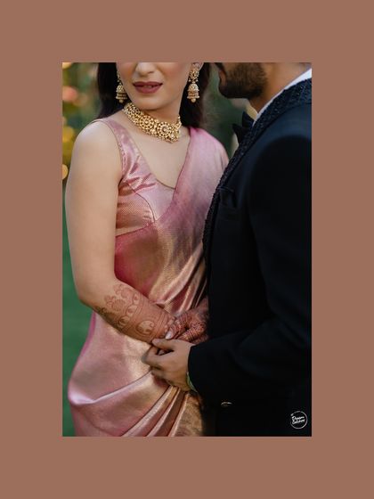 A close-up detail shot focusing on the couple's hands and the bride's beautiful pink saree. We believe in capturing the small details that add to the richness of your wedding story.