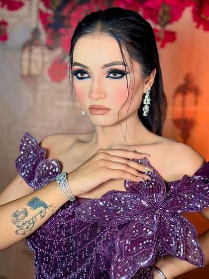 A side profile showcasing the sharp winged liner and the flawless base. The tattoo on her arm adds to the edgy vibe.