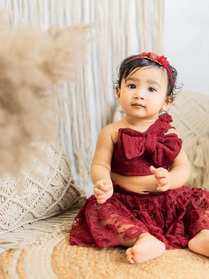 This one-year-old is a little boho princess in her beautiful red lace outfit. A lovely portrait from a custom-styled milestone session.