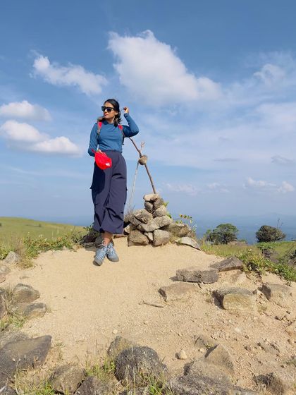 Posing at a trail marker made of stones.