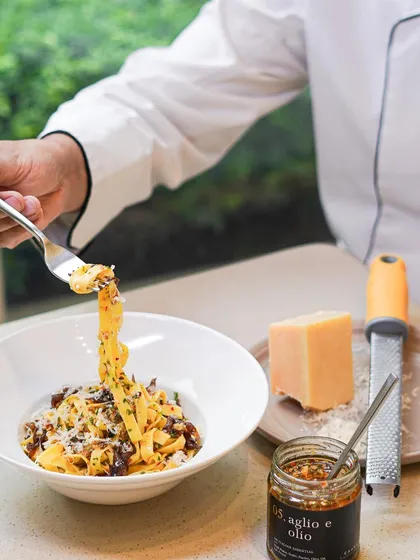A chef twirls a forkful of our fresh fettuccine. This dish is made with our versatile Aglio e Olio mix, showcasing how our pantry products can create a gourmet meal in minutes.