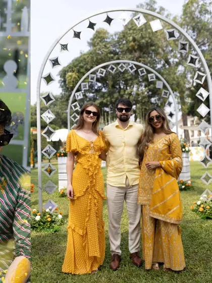 Guests posing in front of the unique mirror-work arches at the Haldi function. The decor provides a perfect photo opportunity.