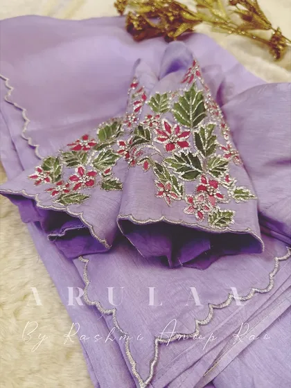 A custom organza saree and blouse set we created for a client. The lavender saree features a delicate scalloped border and is paired with a blouse that has hand-painted and embroidered floral motifs.