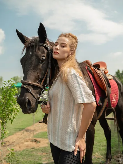 A model stands beside a dark horse, creating a striking contrast. Our diverse range of horses allows for different visual pairings to match any creative brief.