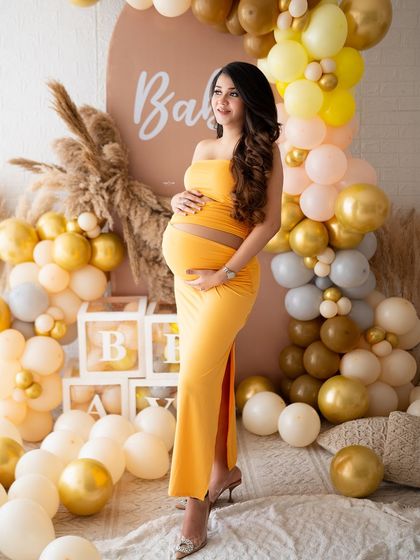 A gorgeous solo shot from a baby shower themed session. The mamma is glowing in a bright yellow dress, surrounded by a beautiful balloon and pampas grass arch.
