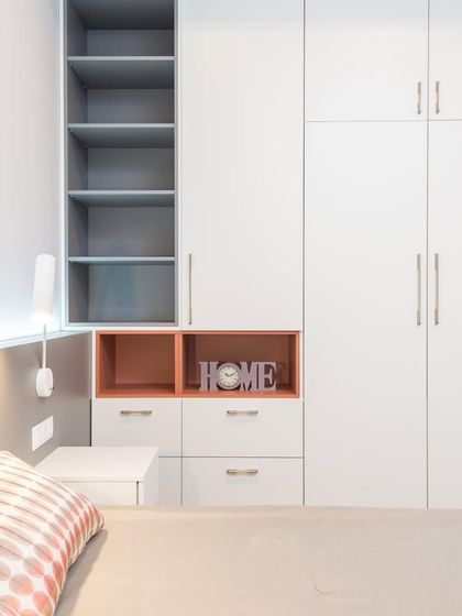 This custom bedroom unit combines a full-sized wardrobe with open shelving and a bedside table, creating a fully integrated and space-efficient solution.