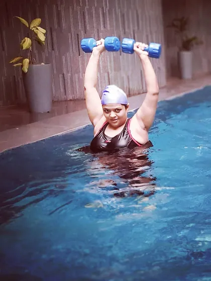 A member performs a shoulder press with aquatic dumbbells. This is a great example of how we build functional strength in a supportive, buoyant environment.