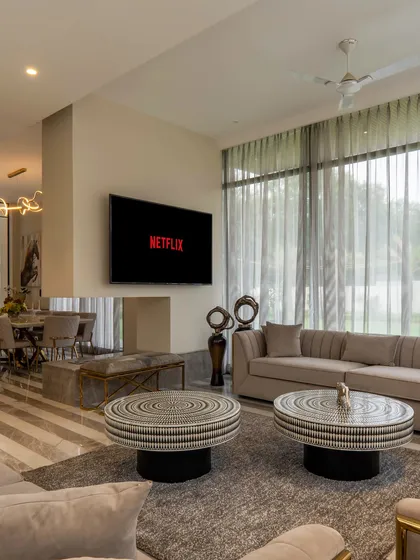 Elegance meets comfort in the drawing room of a modern farmhouse project. The serene and sophisticated space is defined by a palette of beige, white, and gold, with cozy furnishings that add the perfect touch of warmth for everyday living.