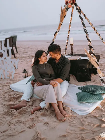 A romantic beach picnic setup for a pre-wedding shoot, complete with a "Will You Marry Me?" sign, capturing the quiet intimacy before the big day.
