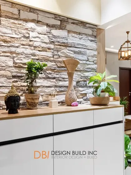 A perspective shot from behind the foyer cabinet, looking into the living room. The stone wall adds a rustic texture that contrasts beautifully with the modern furniture and lighting.