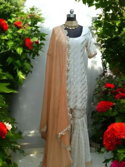 This ethereal cream sharara set is the epitome of dreamy elegance. Crafted in luxurious Burberry fabric with a soft organza dupatta, it's a light, airy, and graceful choice for any sun-kissed celebration or daytime wedding event. The delicate detailing gives it a timeless charm.