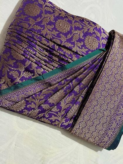 A rich purple Banarasi saree with a green border. The heavy fabric is now easy to manage with these set pleats.