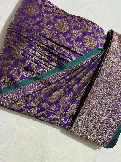 A purple Banarasi saree with a green border, showcasing rich color and texture.