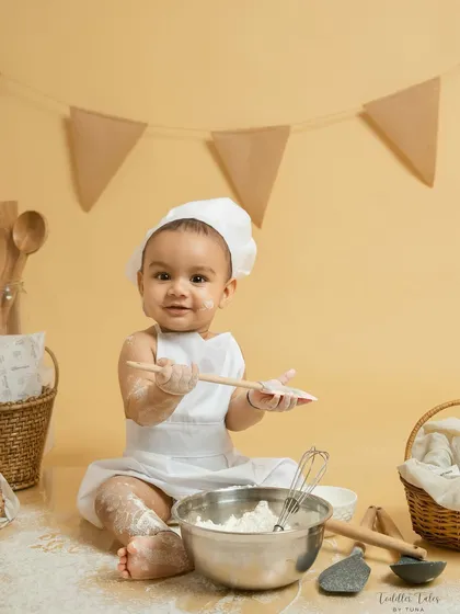 This little chef is ready to mix up some fun, holding wooden spoons with a delightful expression. The interactive props help keep babies engaged and happy throughout the session.