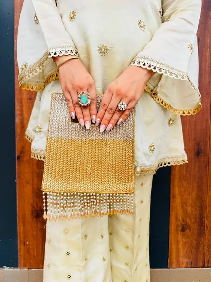 It's all in the details. A statement clutch and bold rings complete this festive look, adding personality and a touch of glamour to the elegant off-white ensemble.