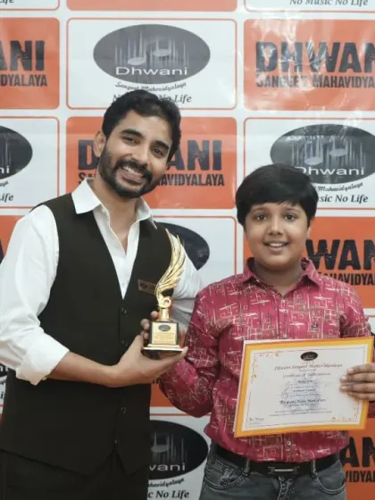 A teacher and student pose with a trophy, a symbol of their shared hard work.