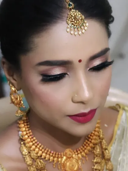 A detailed shot of the bride's eye makeup. The blend of shimmery eyeshadow and perfectly applied eyeliner enhances her eyes, while the red lip adds a classic touch to her traditional South Indian bridal look.
