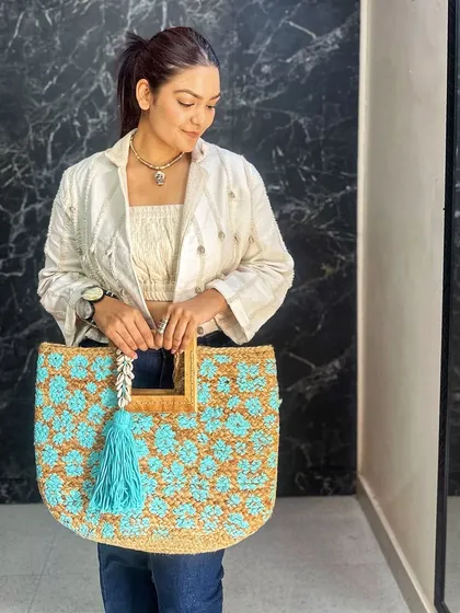 This large tote features beautiful turquoise crochet work on a natural jute base. It's the perfect size for a day out, adding a pop of color and texture to a casual denim and jacket look.