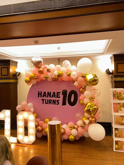 A fun and stylish 10th birthday for Hanae. The pink backdrop is framed by a pink, rose gold, and white balloon ring, with a large light-up '10' and custom name blocks.