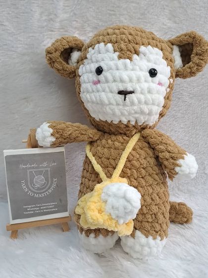 A plush monkey toy with a friendly face and a little banana pouch.