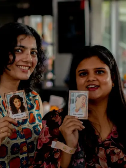Two ladies proudly showing off their Bollywood-themed cards, a fun icebreaker we use at our events.