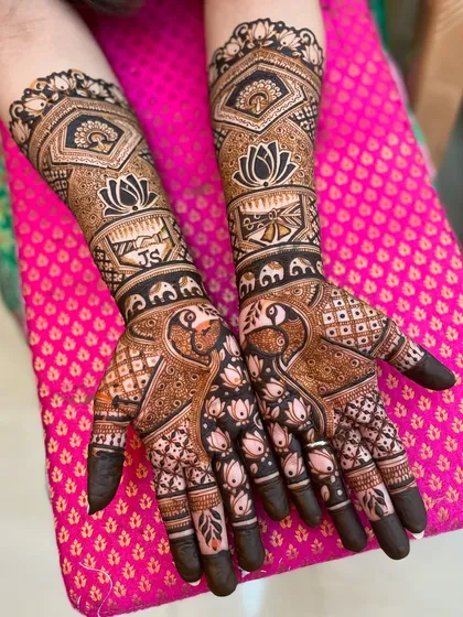 A stunning bridal mehendi with personalized initials "JS". The design is packed with details like peacocks, elephants, and lotus flowers.
