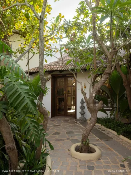 A pathway at Sanctuary Bar, flanked by mature trees and leading towards the entrance of the restored villa. The design respects the existing nature on the site, building the experience around it.