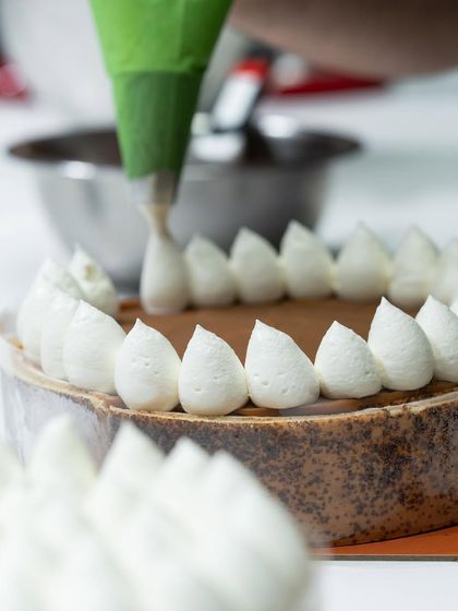 The precision of piping perfect meringue kisses on a cake.