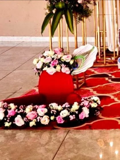 Detailed floral decor at the base of the cradle, featuring fresh flowers and a peacock feather accent for a Krishna-themed naming ceremony.