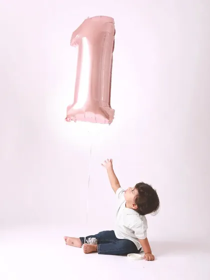 Reaching for the stars, or at least for the balloon. A simple and beautiful portrait capturing a baby's curiosity on his first birthday.