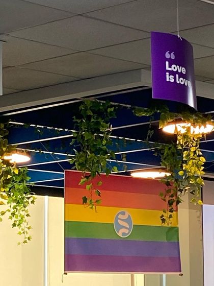 A Pride flag with our logo and a "Love is Love" banner in our office. These decorations are a visible sign of our support for the LGBTQ+ community.