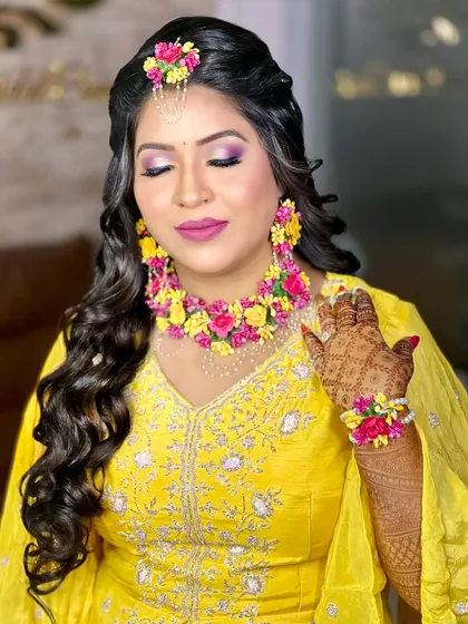 A beautiful Haldi look featuring pink and purple eye makeup and stunning floral jewellery.