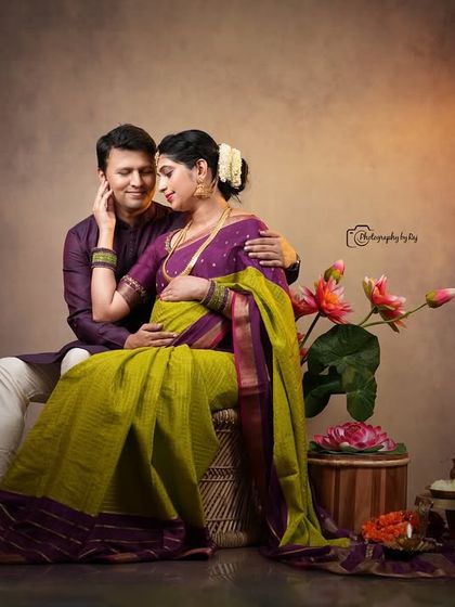 A romantic studio portrait of a couple in traditional attire, seated together with floral props.