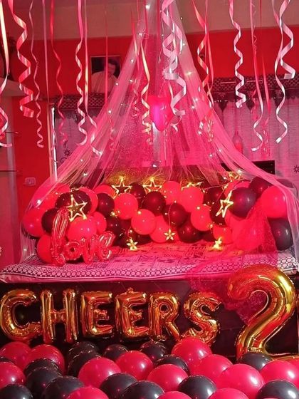 This image showcases the full effect of the 'Cheers' party setup, with a bed canopy, foil balloons, and a floor filled with red and black balloons, ready for a memorable night.